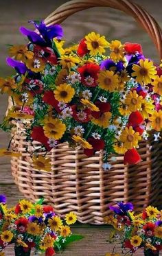 a basket filled with lots of flowers sitting on top of a wooden table next to another basket