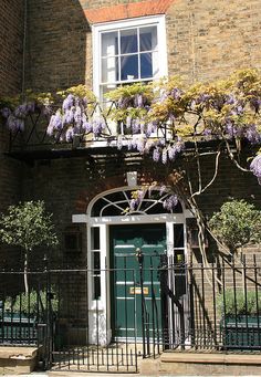 an entrance to a brick building with purple flowers growing on the front door and windows