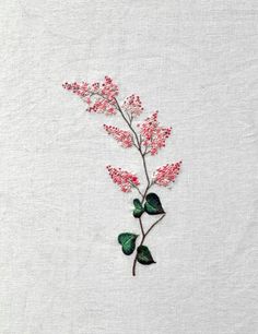 a pink flower with green leaves is on a white sheet that has been embroidered onto it