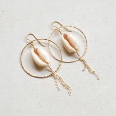 "Beautiful sliced cowrie shells hang within gold filled hammered hoops and have delicate gold chains dangling from them. Hoops measure approximately 1 1/2\". Each cowrie shell is unique so please allow for variations." Handmade 14k Gold Filled Jewelry For The Beach, Handmade 14k Gold Filled Beach Earrings, Handmade 14k Gold Filled Earrings For Beach, Beachy Gold Dangle Earrings, Handmade 14k Gold-filled Earrings For Beach, Gold 14k Gold Filled Earrings For Beach, Bohemian 14k Gold Filled Jewelry For Beach, Bohemian Shell Hoop Earrings For Beach, Handmade Gold Hoop Earrings For Vacation