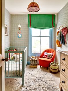 a baby's room with a crib, chair and window