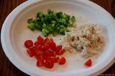 a white plate topped with broccoli, tomatoes and other food on top of a wooden table