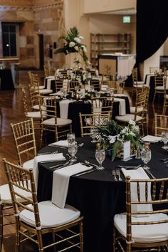 tables and chairs are set up with black linens, white napkins, and greenery