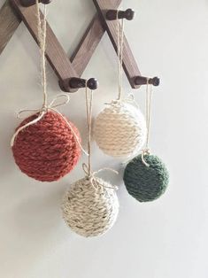 three balls are hanging from the wall with rope and twine attached to them, in different colors