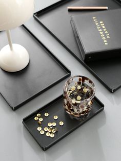 two black trays with gold confetti on them and a white table lamp