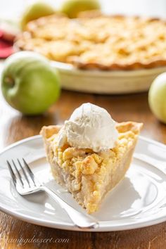 a slice of pie on a plate with ice cream and apples in the back ground