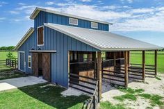 a blue barn with a metal roof and two stalls