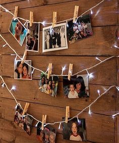 several pictures are hung on clothes pins with string lights strung around them and pinned to wood planks