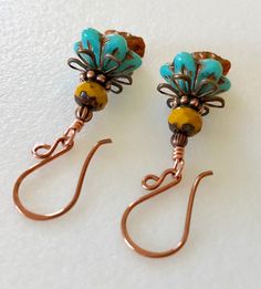 "Adorable new Czech glass premium flower earrings in turquoise and orange opaline with mustard yellow and copper accents. Opaque turquoise Czech glass flower caps with copper Picasso finish are accented with mustard yellow Picasso rondelles on top and dangling at the bottom are darling little Czech glass lily flowers in orange opaline with metallic copper wash. Colorful Czech flowers are wire wrapped in bright copper with antique copper accents. They hang from handmade German copper ear wires. T Handmade Turquoise Flower-shaped Earrings, Turquoise Czech Glass Flower Earrings For Gift, Adjustable Turquoise Flower Earrings Gift, Turquoise Flower Earrings Gift, Nickel Free Yellow Czech Glass Earrings, Nickel-free Yellow Czech Glass Earrings, Turquoise Wire Wrapped Czech Glass Earrings, Turquoise Czech Glass Earrings As Gift, Artisan Turquoise Czech Glass Earrings