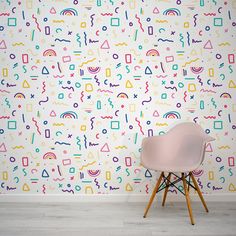 a pink chair sitting in front of a colorful wall