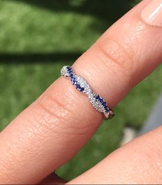 a woman's hand with a blue and white diamond ring on top of her finger