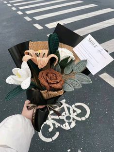 a person holding a bouquet of flowers in their hand on the side of the road