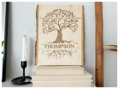 a wooden sign with a tree on it next to some books and a candle holder