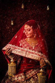 a woman dressed in red and gold is holding a golden vase with her hands on it