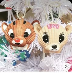 two ornaments hanging from a christmas tree with white branches and decorations in the shape of animals