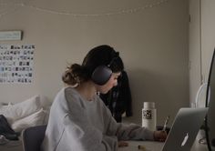 a woman sitting in front of a laptop computer wearing headphones