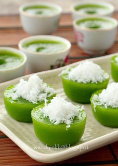 small green desserts with white toppings on a serving platter next to cups