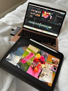 an open laptop computer sitting on top of a bed next to a phone and tablet