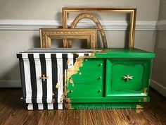 an old dresser painted green and black with gold stars on the top, next to a striped box