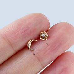 a person's hand with a small gold sun and moon ring on it