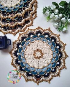 two crocheted doily designs next to a blue cup holder and white flowers