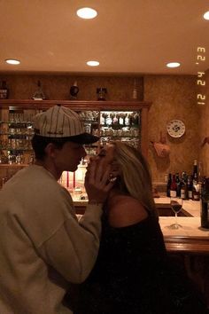 a man standing next to a woman in front of a bar filled with liquor bottles