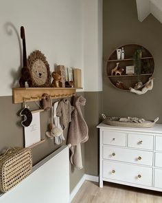 a white dresser sitting next to a wall with stuffed animals hanging on it's sides