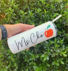 a hand holding an apple water bottle with writing on the side and a straw in it