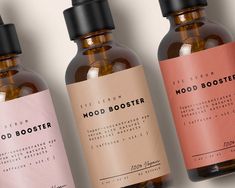 three bottles of wood booster sit side by side on a white surface with pink and brown labels