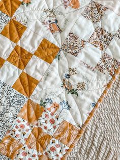 an orange and white quilt on top of a bed