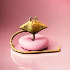 a gold mouse on top of a pink donut