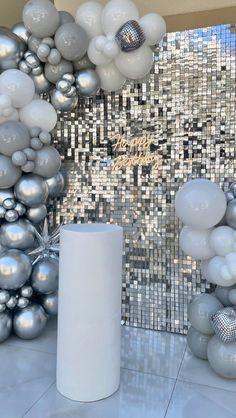 silver and white balloons in front of a mosaic wall