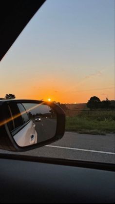 the sun is setting in the distance as seen from a car's side view mirror