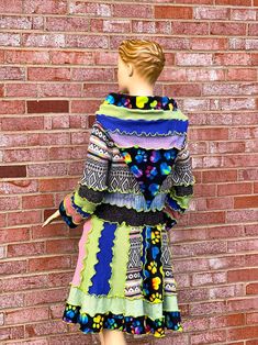 a mannequin wearing a multicolored dress standing in front of a brick wall