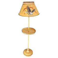 a lamp with an eagle on it and a yellow shade over the top that is sitting on a stand