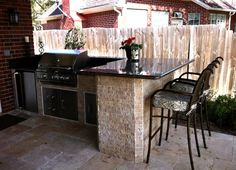 an outdoor kitchen with grill and bar stools