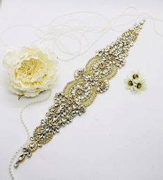 "This listing is for 1 Gold Wedding Applique made with clear rhinestones set in gold prongs, Gold seed beads and ivory pearls. Sewed onto a mesh/resin paper so you can sew, glue or iron this on. Measurements: 17\" long x 3\" at it's widest Metal Color: Gold Application: Sew, glue or iron on This is for DIY projects, would be perfect for: garters, belts, hats, headbands or bags! This is NOT attached to a ribbon." Gold Cubic Zirconia Wedding Jewelry, Gold Cubic Zirconia Bridal Accessories For Wedding, Elegant Gold Bridal Accessories With Cubic Zirconia, Gold Diamond Bridal Necklace For Wedding, Crystal Bridal Accessories With Rhinestones For Bride, Gold Embellished Bridal Accessories For Party, Elegant Bling Bridal Belt For Wedding, Glamorous Bridal Necklace With Diamond Accents For Wedding, Gold Jeweled Bridal Necklace For Party