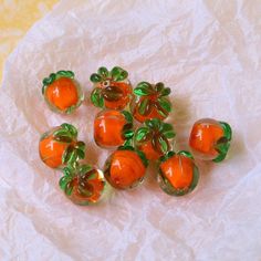 small orange glass beads with green leaves on them