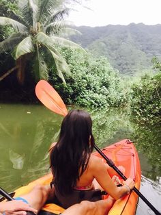 a man and woman in a kayak paddling down a river