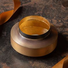 a close up of a metal object on a table with some brown ribbon around it