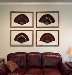 a living room with leather couches and pictures on the wall above them in wood frames