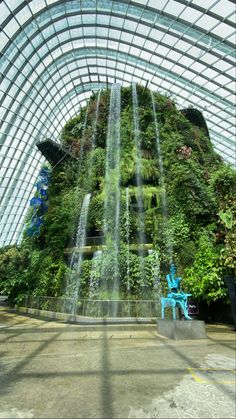 an indoor waterfall in the middle of a building with lots of greenery on it