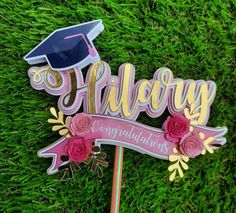 a cake topper that says,'congratulations'with flowers and a graduation cap on it