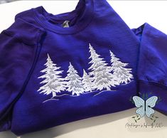 Add some winter whimsy to your wardrobe with our Winter Trees Embroidered Crewneck Sweatshirt! Made with soft, cozy fabric, this purple sweatshirt boasts charming embroidered trees, perfect for the chilly season. Stay stylish and comfortable all winter long. This crewneck is unisex. This is a physical product. Crewneck is embroidered. Purple Cotton Winter Tops, Winter Purple Cotton Tops, Purple Cotton Tops For Winter, Cozy Purple Sweatshirt For Winter, Embroidered Trees, Winter Whimsy, Rhinestone Hoodie, Purple Sweatshirt, Nurse Hat