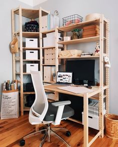 a computer desk sitting on top of a wooden floor next to a shelf filled with boxes