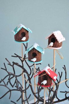 three bird houses on sticks with snow on them in the shape of trees and branches