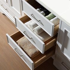 an open drawer in a bathroom with towels and other items on the shelf next to it