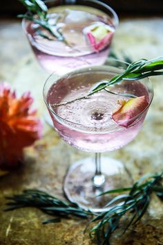 two glasses filled with pink liquid and flowers