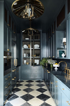 a kitchen with black and white checkered flooring, gold accents and chandelier