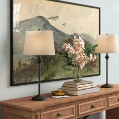 two vases with flowers are sitting on a table in front of a framed painting